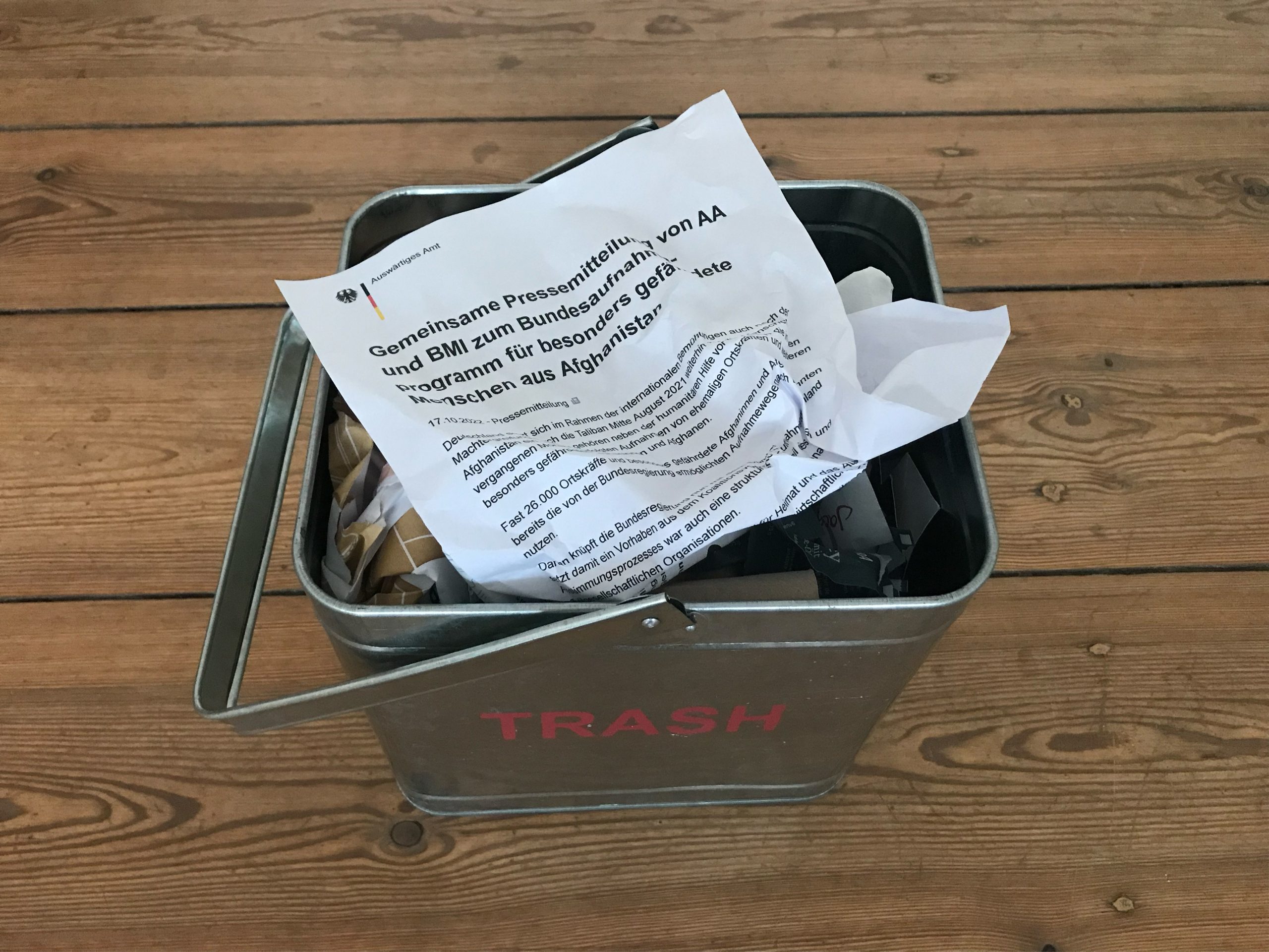 Oben auf einem Papierkork liegt die etwas zerknüllte Pressemitteilung des Auswertigen Amts zum Bundesaufnahmeprogramm für Menschen aus Afghanistan.