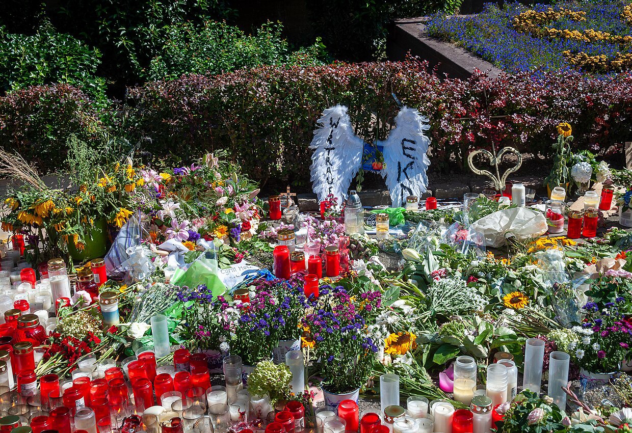 viele Blumen und Grabkerzen liegen auf dem Bürgersteig
