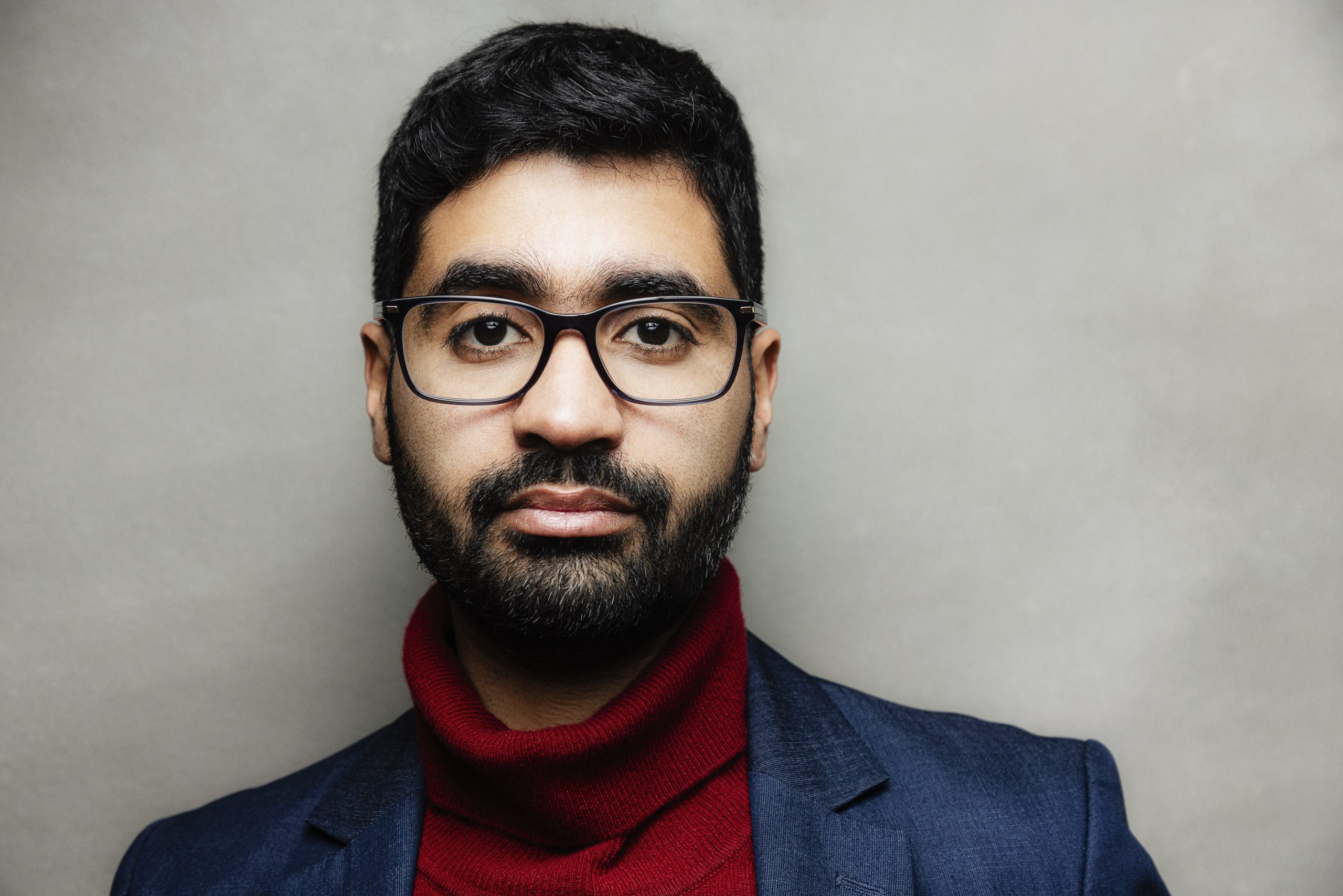 Porträt, ein Mann mit Brille und Bart guckt den Betrachtenden direkt an.